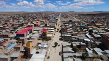 Aerial shot drone ascends over town with dirt roads and square blocks