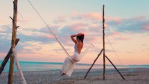 Girl on the Swing by the Calm Ocean at Sunset