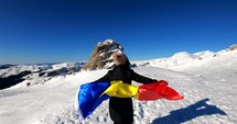 Girl running with the Romanian Flag on top of The Bucegi Mountains, towards the Sphinx rock in Romania.