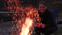 Young Woman Enjoying Campfire By Lake At Dusk