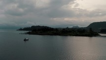 Serene Scenery Of Lake With Passenger Boat In Lake Atitlan, Guatemala At Sunrise - aerial drone shot	