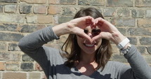 Young hippy woman makes heart with hands close up