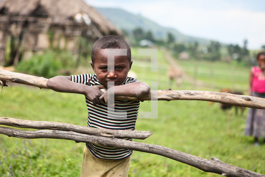 Young boy leaning on wooden fence