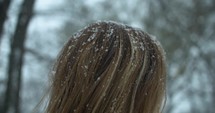 Slow motion snow flakes fall on woman's hair during winter snow storm.