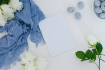 white roses, blue scarf, speckled blue eggs, white background, notepad 