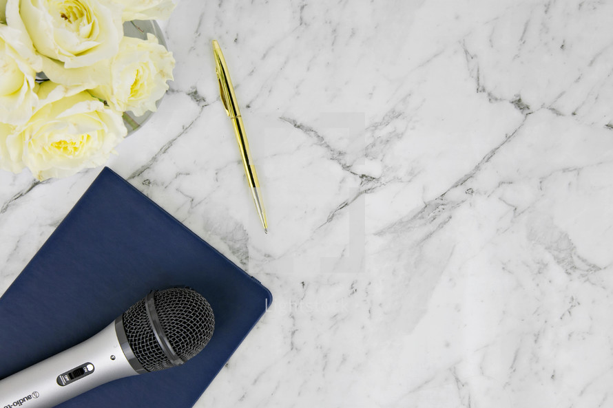 notebook, roses, microphone, and pen on a marble background 