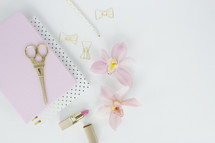 lipstick, clipboard, scissors, orchid, paper clips, gold, pink, Eiffel tower, pencil, feminine, desk, white background 