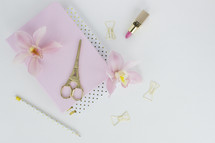 lipstick, clipboard, scissors, orchid, paper clips, gold, pink, Eiffel tower, pencil, feminine, desk, white background 