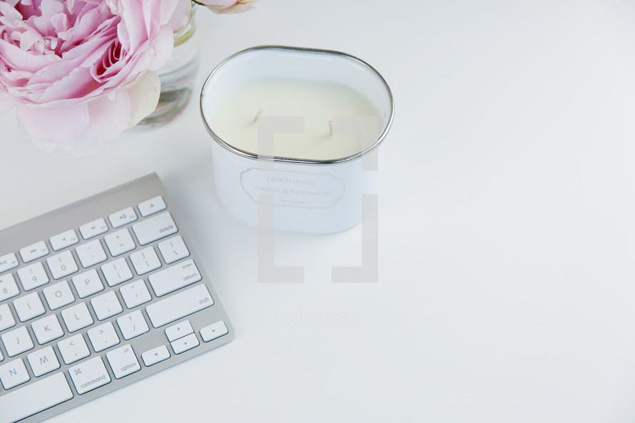 computer keyboard, candle, and pink peony on a white background 