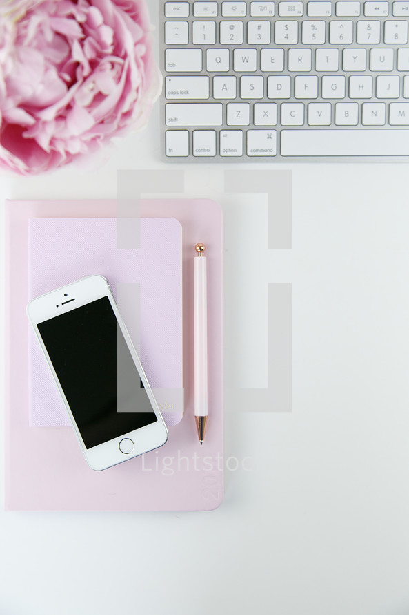 iPhone, pen, journal, computer keyboard, and pink peony on a white background 