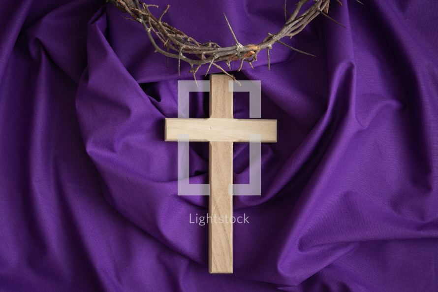 Cross and crown of thorns on a purple cloth background