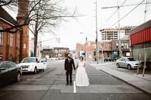 bride and groom standing in the middle of a downtown street 