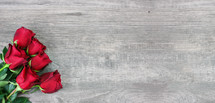 Bouquet of beautiful red roses on light wood background with copy space, horizontal