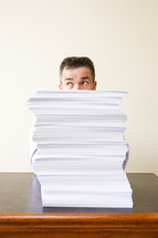 Caucasian businessman behind a stack of paper