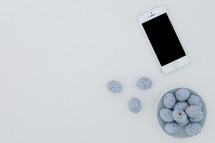 speckled blue eggs in a bowl and iPhone on a white background 