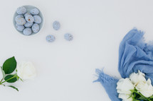 white roses, blue scarf, speckled blue eggs, white background 