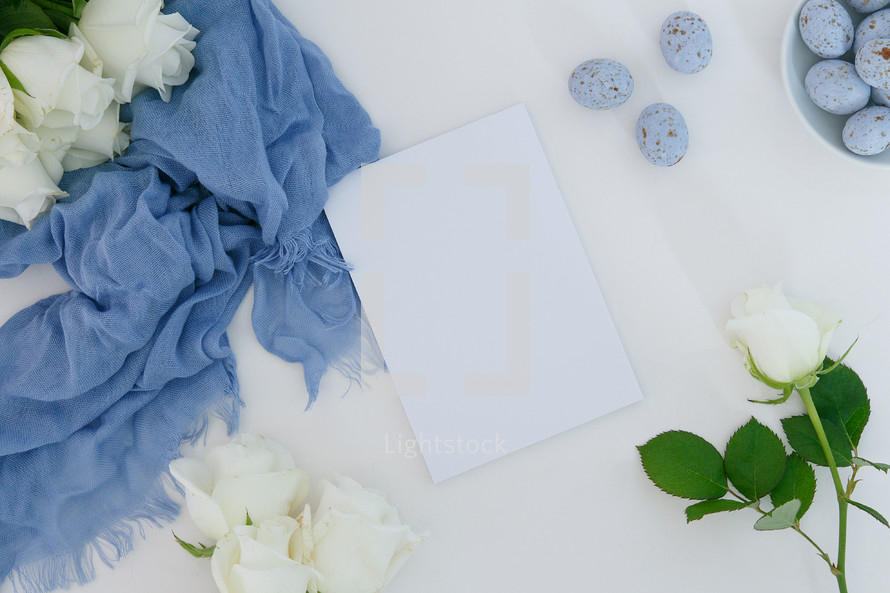 white roses, blue scarf, speckled blue eggs, white background, notepad 