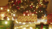 Illuminated Christmas gift box under the tree on the white carpet