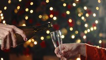 Pouring Champagne On New Year's Eve into the glasses against the tree