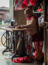 a woman in India sewing fabrics on a sewing machine 