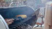 Man moving charcoal while barbecuing meat and veggies on grill during cookout party with friends. Tilt-up shot
