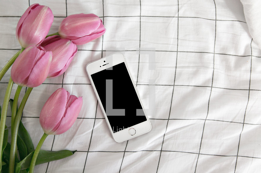 tulips and cellphone on a bed 