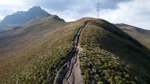 Aerial shot drone flies low on hiking path toward volcano