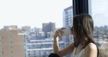 Woman sipping as she looks at city skyline