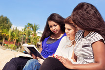 three friends reading a Bible outdoors 