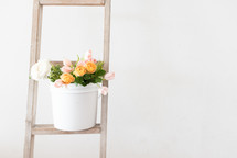 roses in a bucket on a ladder 