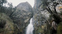 Waterfall Strongly Flows From Towering Rocky Mountain In Cayambe Coca Reserve Hike Near Papallacta, Ecuador. Slow Motion