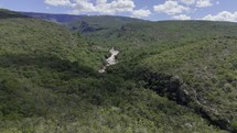 Drone hovers high over valley on partially cloudy afternoon