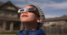 Young boy watching solar eclipse outside home -  close up on face