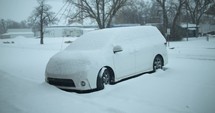 Winter snow storm in small town. Snowfall covering a car, vehicle during snow fall in cinematic slow motion.
