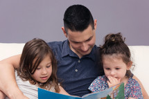 Man Reading Holy Bible to his two daughter 