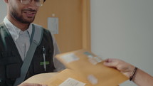 Young male postal service worker delivering express mail to female recipient at home, asking to sign a document, then saying bye and leaving
