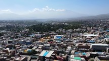 Aerial shot drone flies over city in morning toward Chachani volcano
