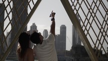 A couple, man and woman, tourists in Dubai pointing and looking up to sky at Burj Khalifa with distant buildings and skyscrapers at the Dubai mall in the middle east country of United Arab Emirates.