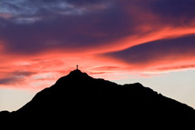 cross on a mountain peak at sunset 