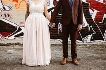 a bride and groom standing in front of a graffiti covered wall 