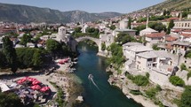 Aerial view circling the iconic Stari Most with motor boat travelling towards the old arched bridge in Mostar, Bosnia