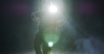 silhouette of a female dancer performing hip hop dance with light and smoke background