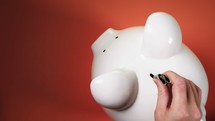 placing money in a piggy bank 
