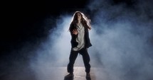 Young female dancer performing wild hip hop dance with strobe light and smoke background