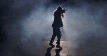 Young female dancer performing wild hip hop dance with strobe light and smoke background