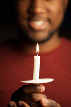 An African American man holding a candle at a worship service 