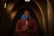 a man holding a candle at a Christmas Eve service 
