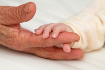 Infant holding grandmother's finger.