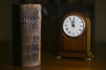 old leather Bible and clock on a table 