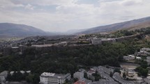 Aerial drone shot of a historic Fortress in Gjirokastra, Albania, showcasing traditional stone houses surrounding it.